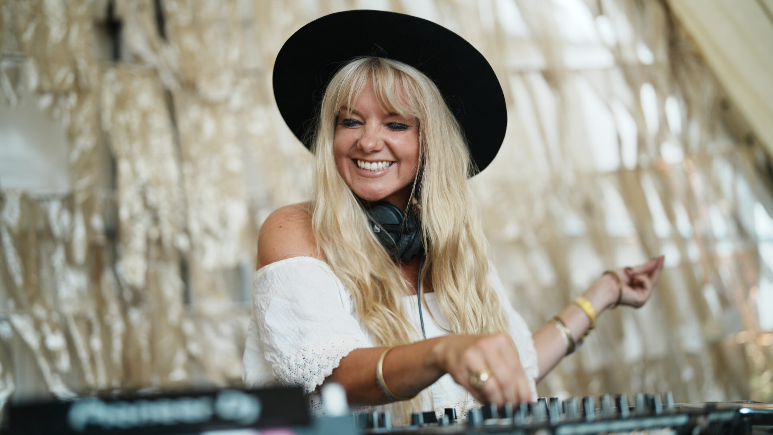 A DJ in a wide-brimmed hat playing a set behind the decks