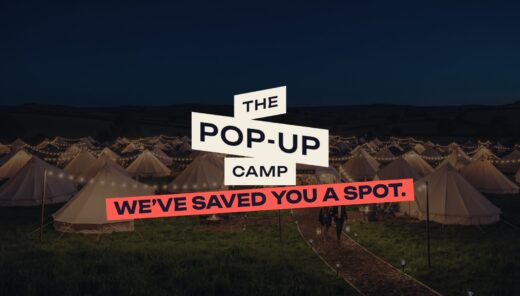 Bell tents lit with festoon lights at night with The Pop-Up Camp logo and the line We've saved you a spot